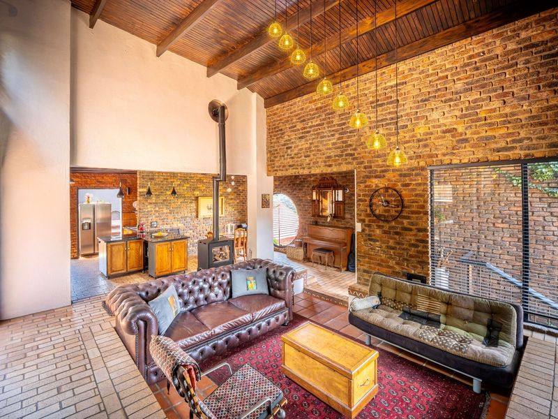 Spacious open-plan living area featuring exposed brick walls, high vaulted timber ceilings, a wood-burning fireplace, and seamless flow to the adjacent kitchen.