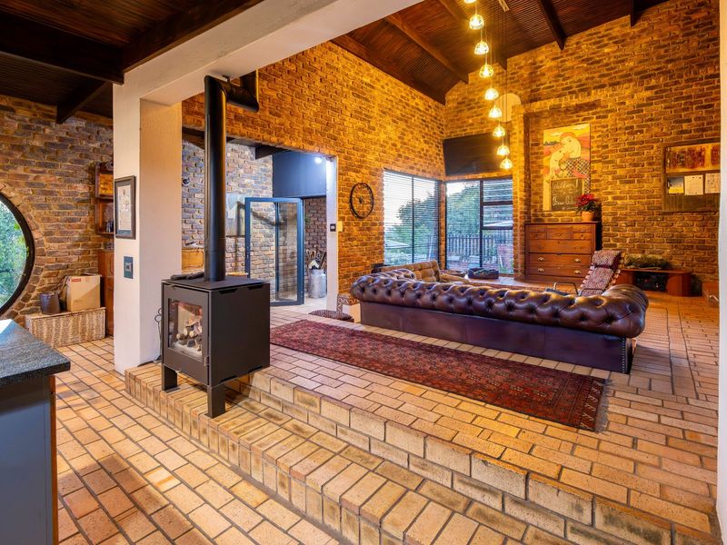 Spacious living area featuring exposed brick walls, vaulted timber ceiling, raised brick flooring, and a modern freestanding fireplace.