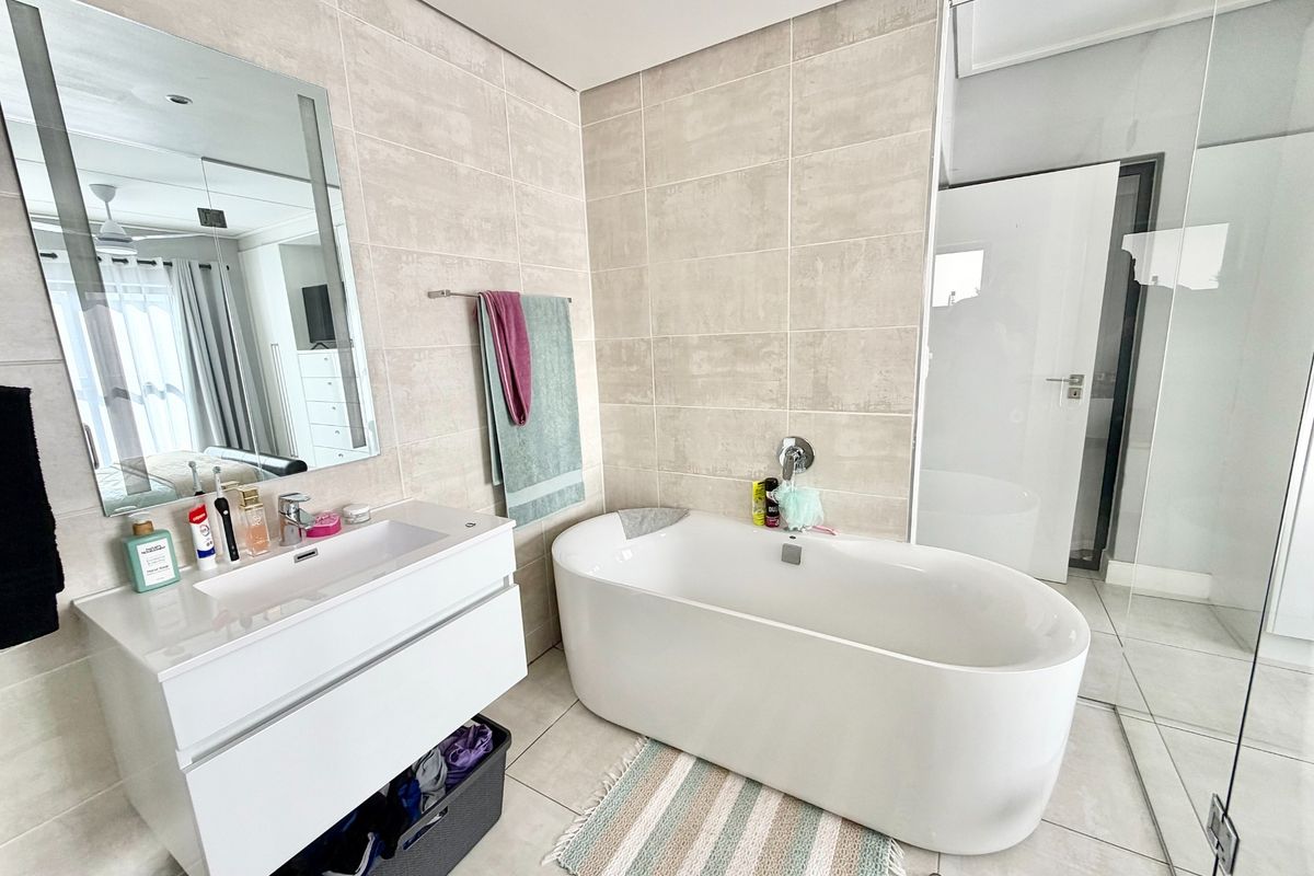 Modern bathroom featuring a sleek wall-mounted vanity, a contemporary freestanding bathtub, and large-format neutral wall tiles.