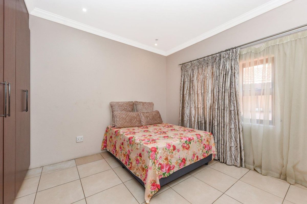 A bedroom featuring tiled flooring, built-in cupboards, and crown molding, providing a functional and neutral space.