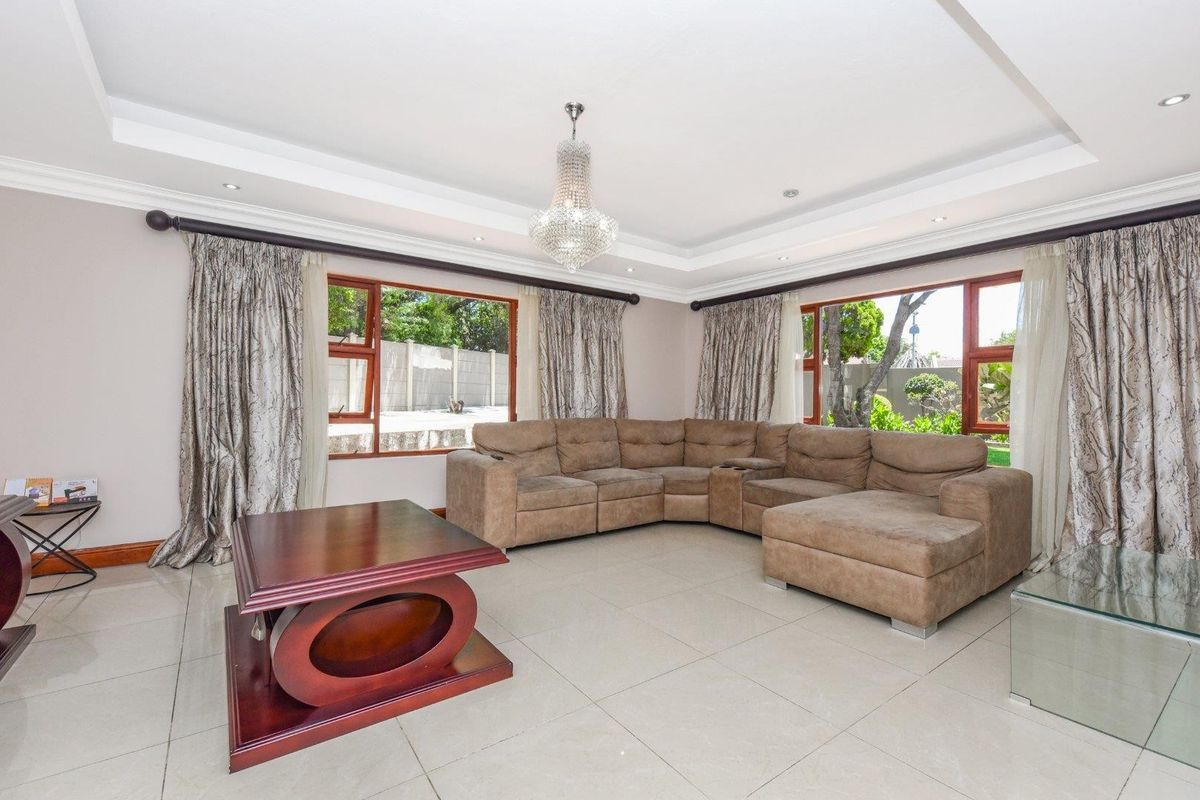 Spacious living room featuring large windows, recessed tray ceiling with downlights, and polished floor tiles.