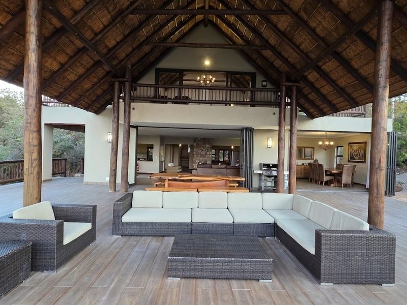 Expansive covered patio featuring a high thatched roof, timber decking, and seamless flow into the open-plan living and dining areas.