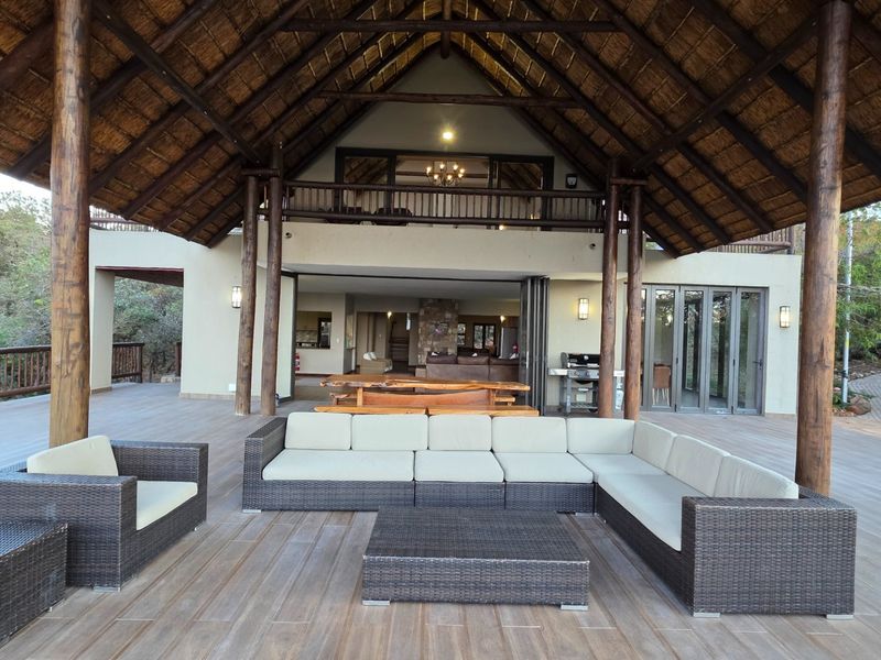 Expansive covered patio featuring a high thatched roof, timber support columns, and seamless flow into the open-plan interior living area.