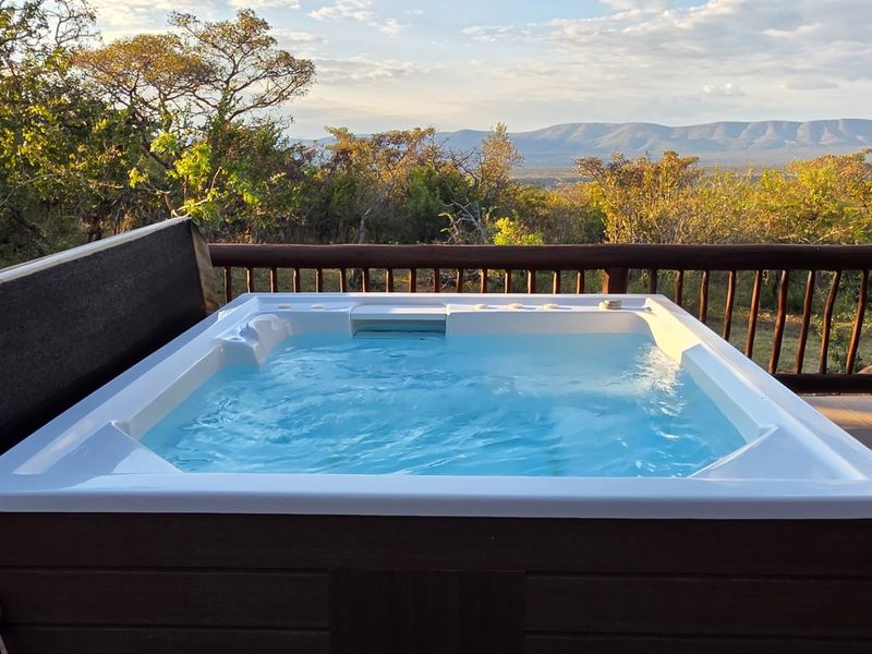 Outdoor deck featuring a built-in hot tub with scenic mountain and bushveld views.