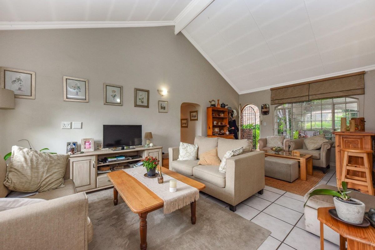 Spacious living room featuring high vaulted ceilings, tiled flooring, and large windows providing natural light and access to the outdoor area.