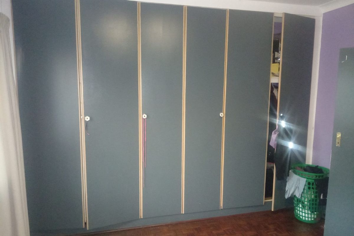 Bedroom featuring a large wall-to-wall built-in wardrobe with dark grey finish and parquet flooring.