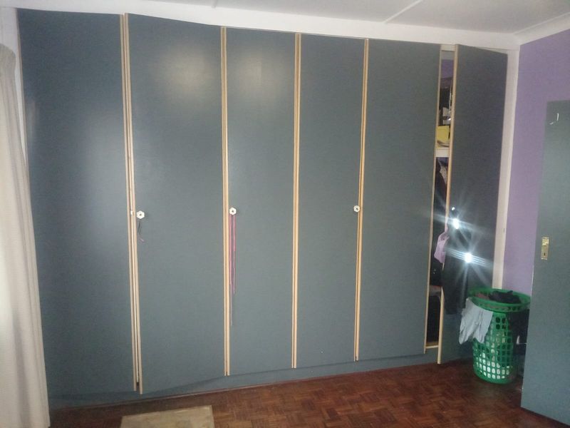 Bedroom featuring a large wall-to-wall built-in wardrobe with dark grey finish and parquet flooring.