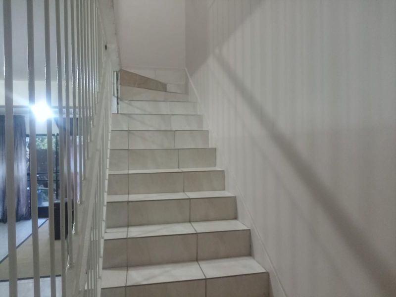 A staircase featuring tiled steps and a white metal balustrade, providing access between levels within the apartment.