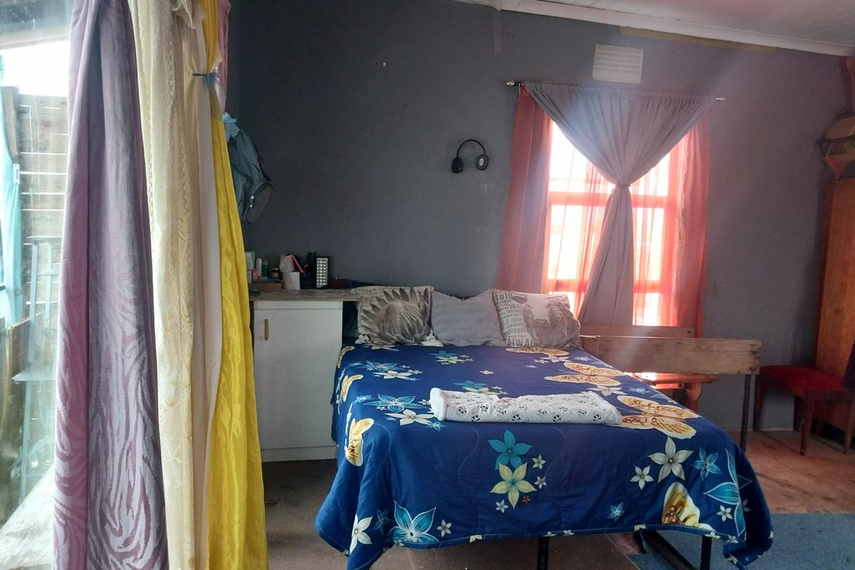 A bedroom featuring a window with curtains and wall-mounted lighting, requiring cosmetic updates to improve the overall finish and condition of the space.