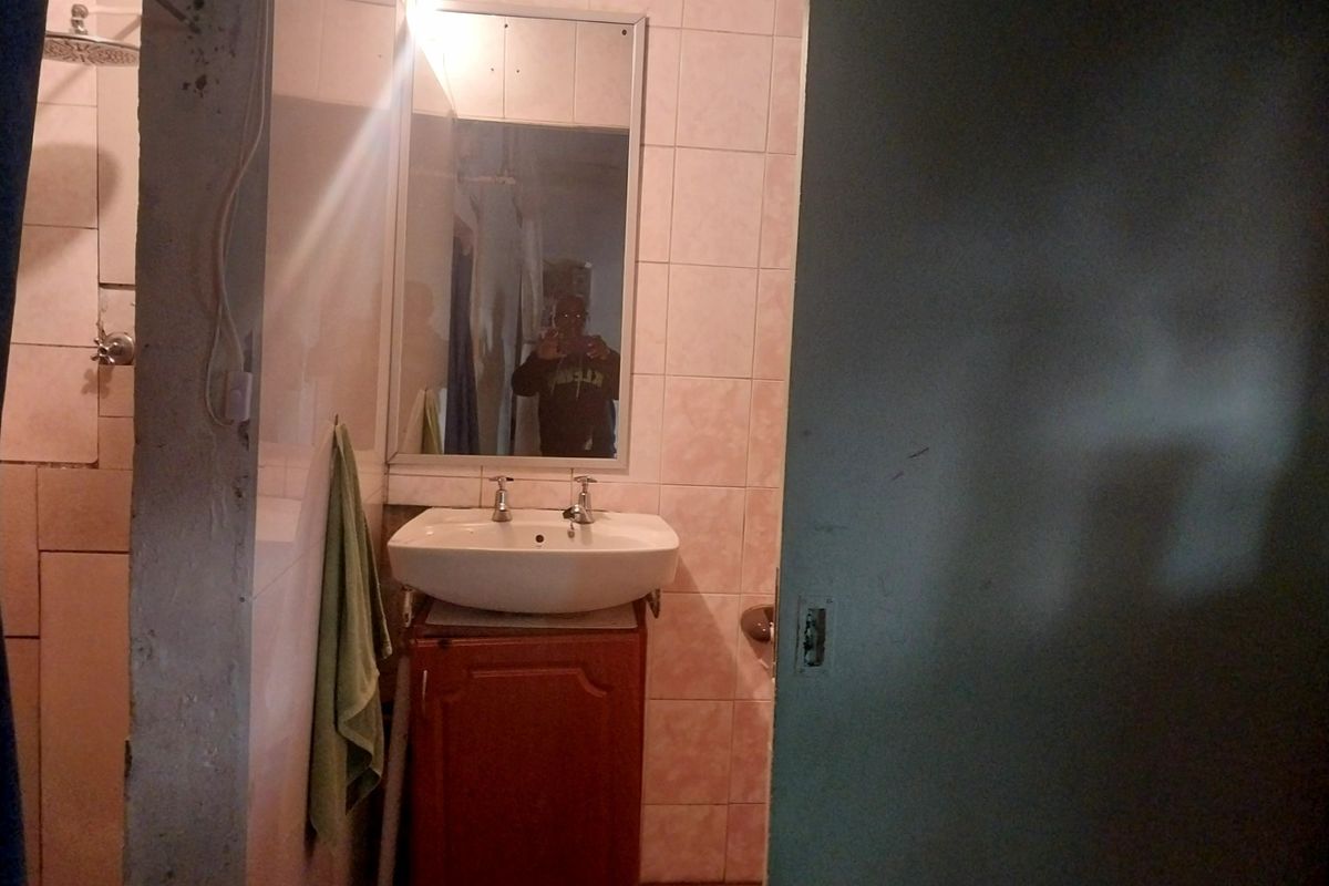 A dated bathroom featuring a vanity cabinet with a ceramic basin, wall mirror, and tiled walls, requiring cosmetic updates to improve its overall appeal.