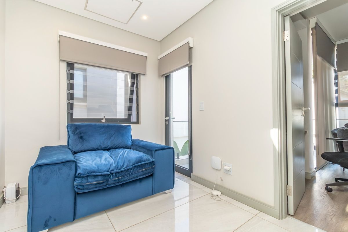 A bright, modern room featuring polished porcelain floor tiles, neutral walls, roller blinds, and a glass door leading to an outdoor area.