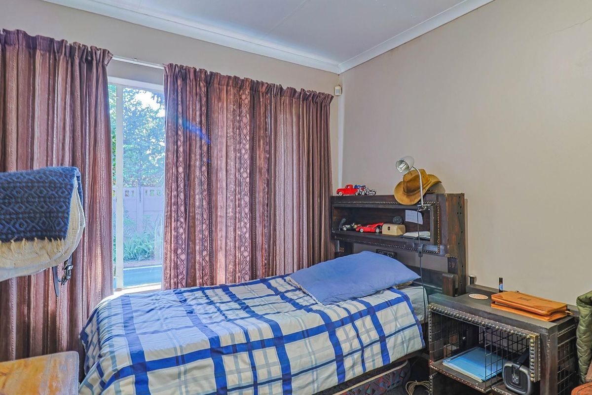A bedroom featuring a sliding glass door with access to the exterior, providing natural light and garden views.