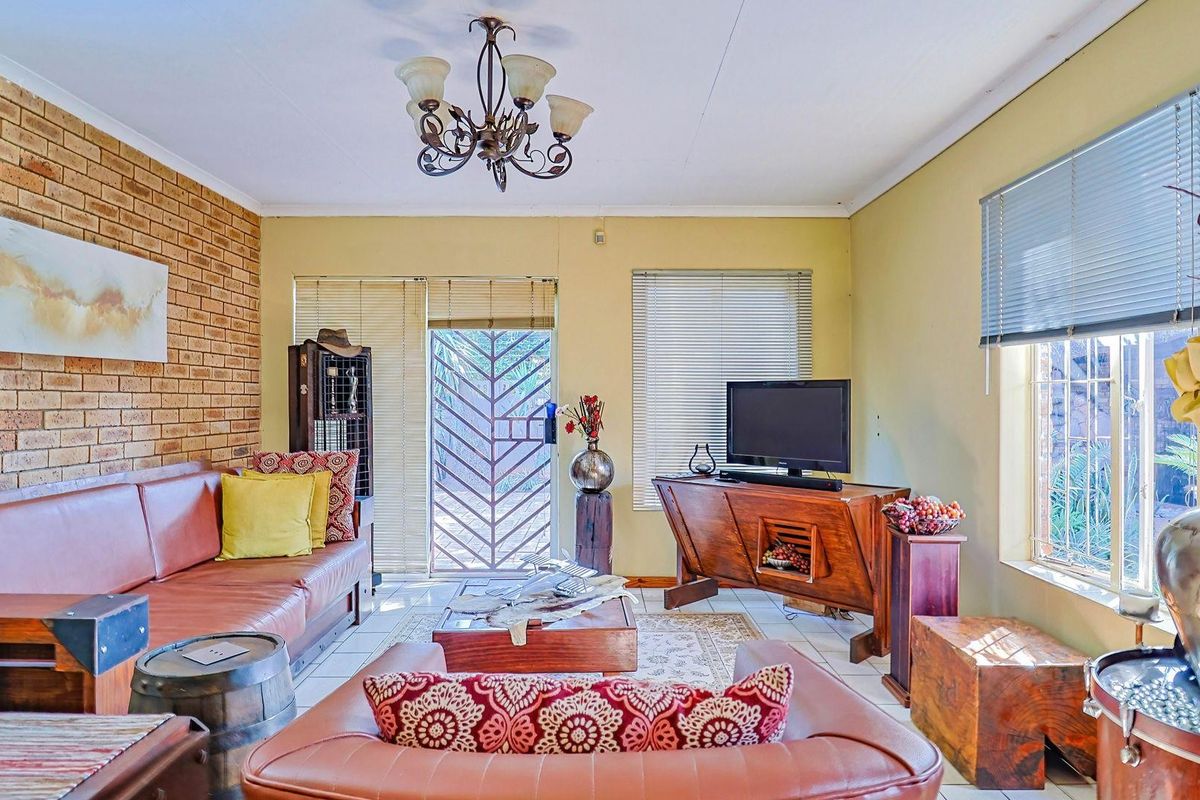 A living room featuring a brick feature wall, tiled flooring, and a security gate leading to the exterior.