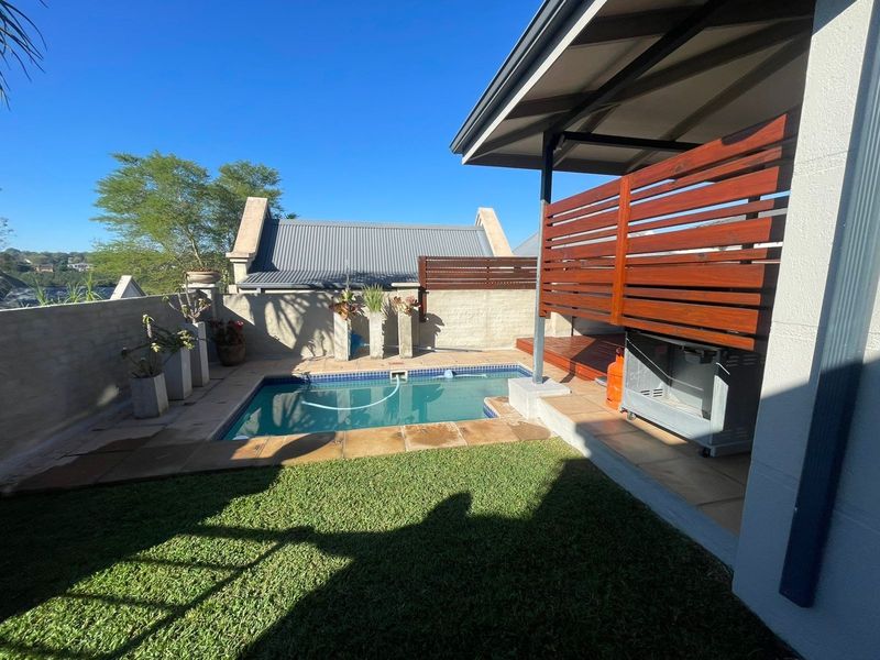 Outdoor pool area featuring a small swimming pool, paved surround, and a covered patio with a timber privacy screen.