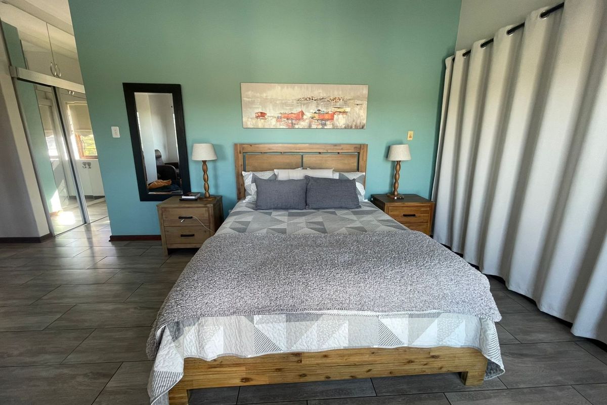 A well-maintained bedroom featuring tiled flooring, a feature wall, and built-in sliding door wardrobes, offering a clean and functional living space.