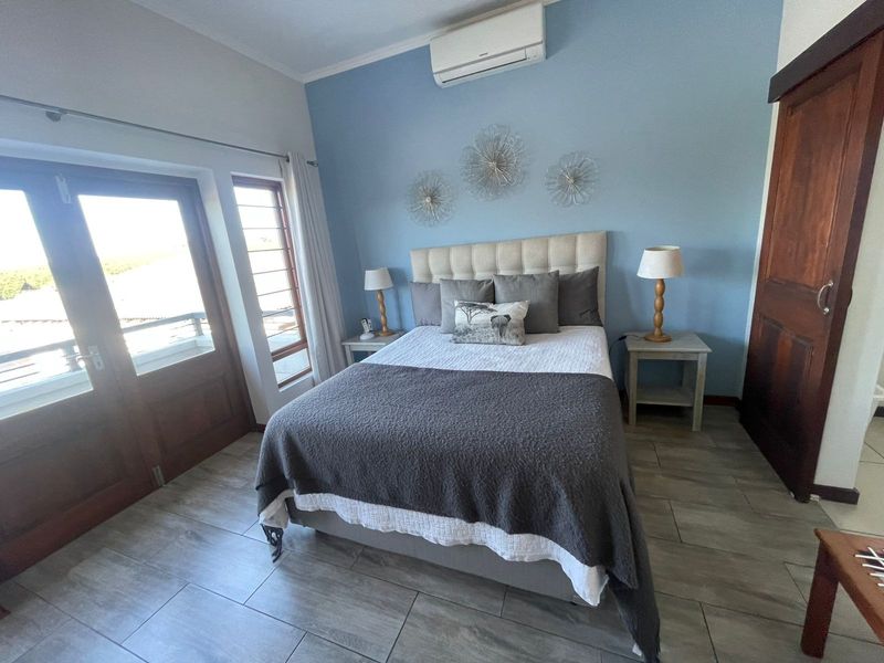 A well-maintained bedroom featuring tiled flooring, a split-system air conditioner, and direct access to an outdoor area through timber-framed glass doors.
