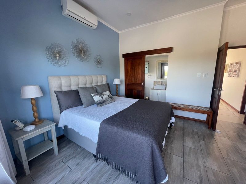 A well-maintained bedroom featuring tiled flooring, a split-system air conditioner, and a sliding barn door leading to an en-suite vanity area.