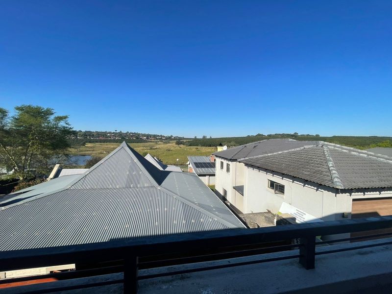 Elevated view overlooking neighbouring properties, rooftops, and the surrounding landscape under a clear blue sky.