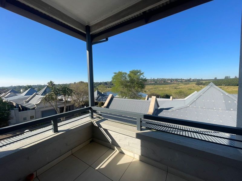 A covered balcony featuring tiled flooring and a metal balustrade, offering elevated views over the surrounding estate and landscape.