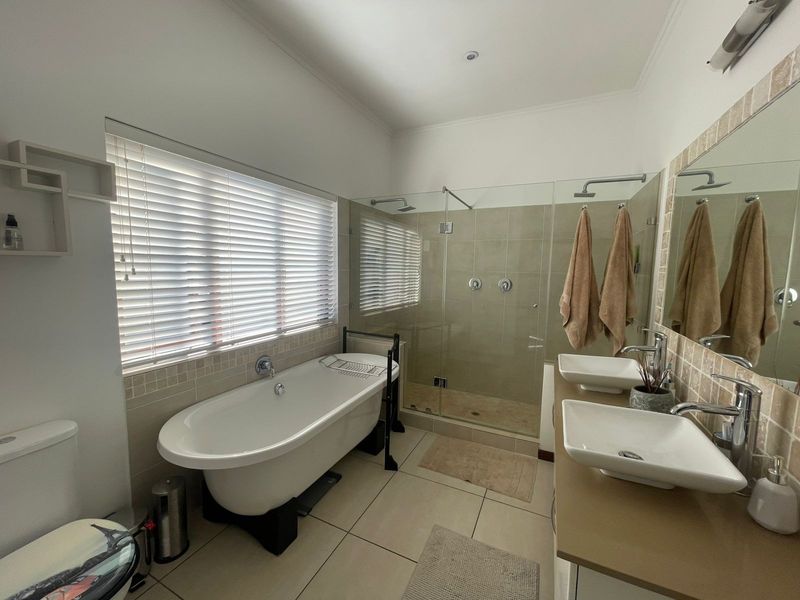 Modern bathroom featuring a freestanding bathtub, a spacious walk-in glass shower, and a dual-sink vanity with contemporary fixtures.