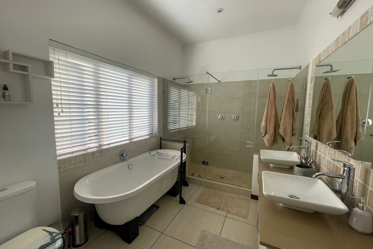 Modern bathroom featuring a freestanding bathtub, a spacious walk-in glass shower, and a dual-sink vanity with contemporary fixtures.
