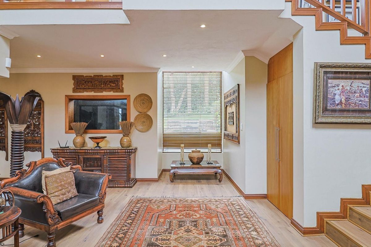 Spacious living area featuring a prominent wooden staircase, built-in cabinetry, recessed lighting, and light-toned laminate flooring with a warm, inviting atmosphere.