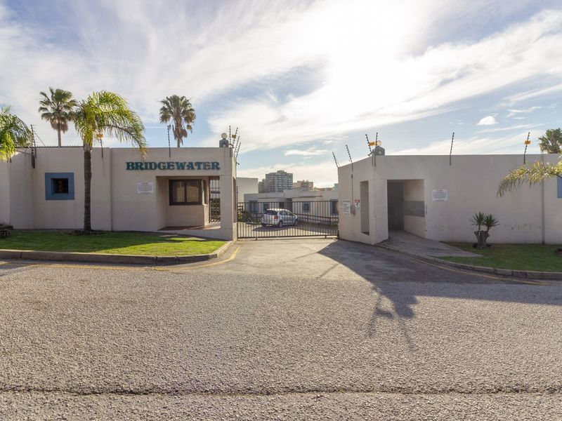 The front entrance of the Bridgewater apartment complex, featuring a secure gated access point with perimeter wall and electric fencing.