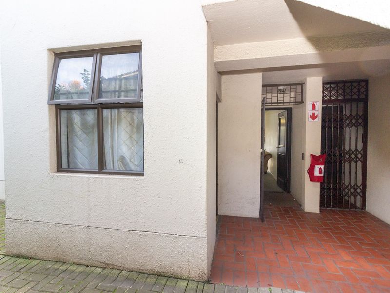 Exterior entrance area featuring terracotta tiling, a security gate, and a fire safety station, providing access to the apartment unit.