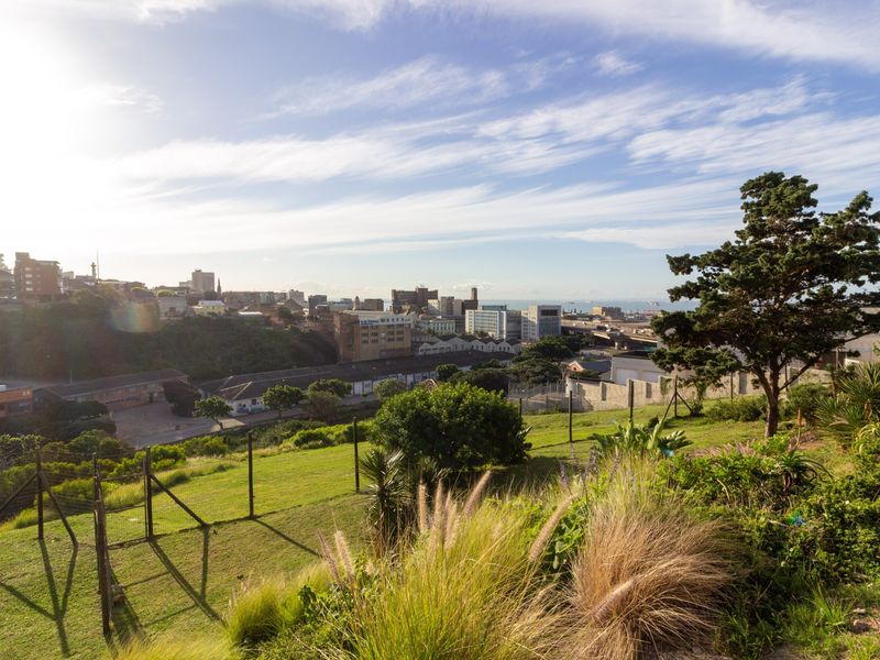 An elevated view overlooking the surrounding urban landscape and coastline, featuring a well-maintained grassy garden area in the foreground.