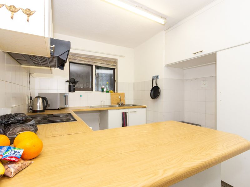 A functional kitchen featuring laminate countertops, built-in cabinetry, an electric hob, and a tiled splashback, offering a practical layout for daily meal preparation.