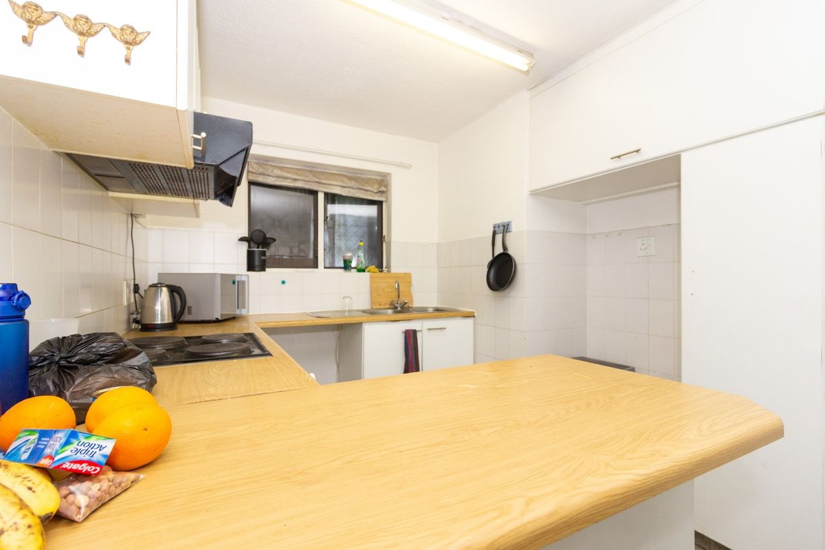 A functional kitchen featuring laminate countertops, built-in cabinetry, an electric hob, and a tiled splashback, offering a practical layout for daily meal preparation.
