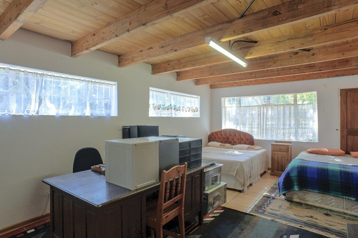 Spacious bedroom featuring exposed timber beam ceilings, tiled flooring, and large windows providing ample natural light.