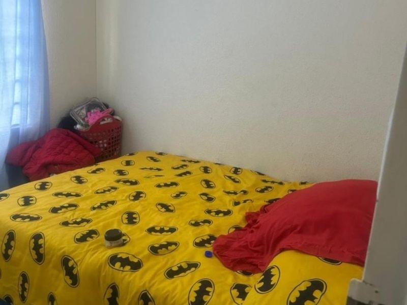 A standard bedroom featuring tiled flooring and a window with curtain fixtures.