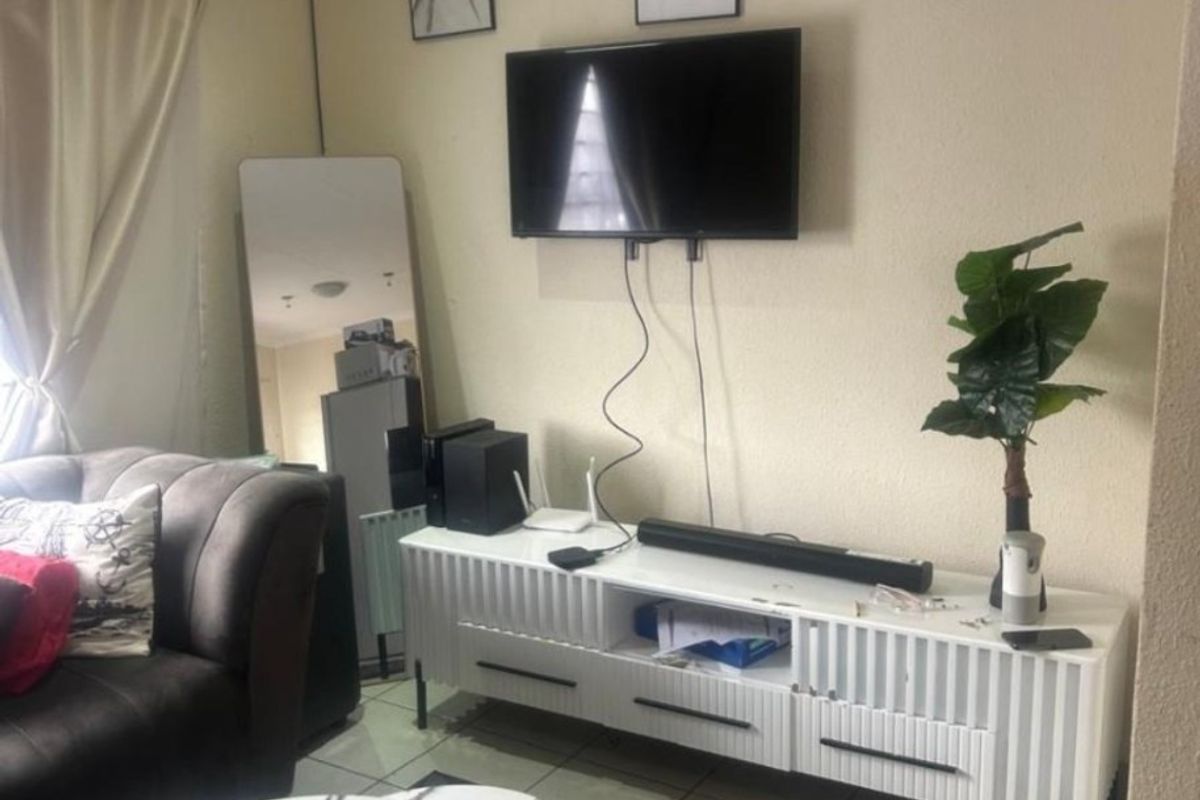 A living room area featuring tiled flooring and a wall-mounted television setup.