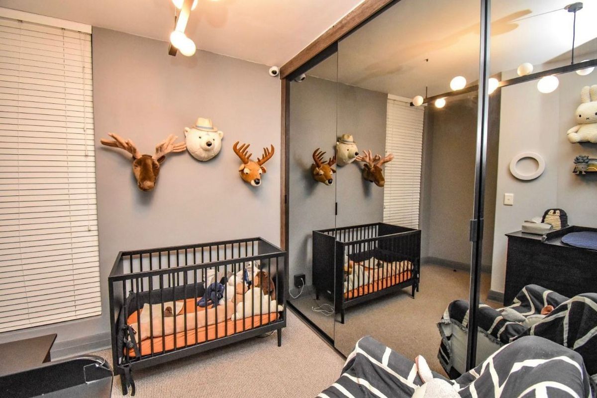 A bedroom featuring neutral wall tones, carpeted flooring, and large floor-to-ceiling mirrored sliding wardrobe doors.