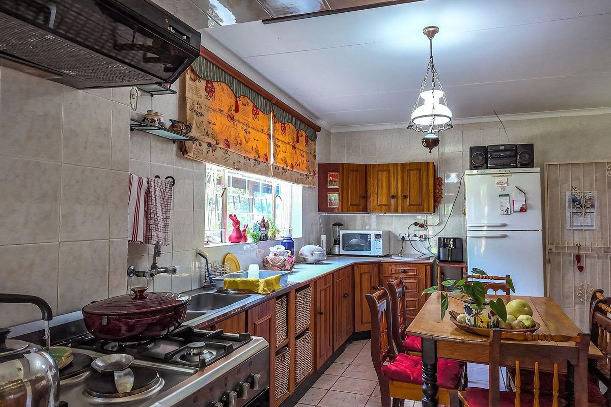 A functional kitchen featuring wooden cabinetry, tiled splashbacks, a gas stove with extractor fan, and an integrated dining area.