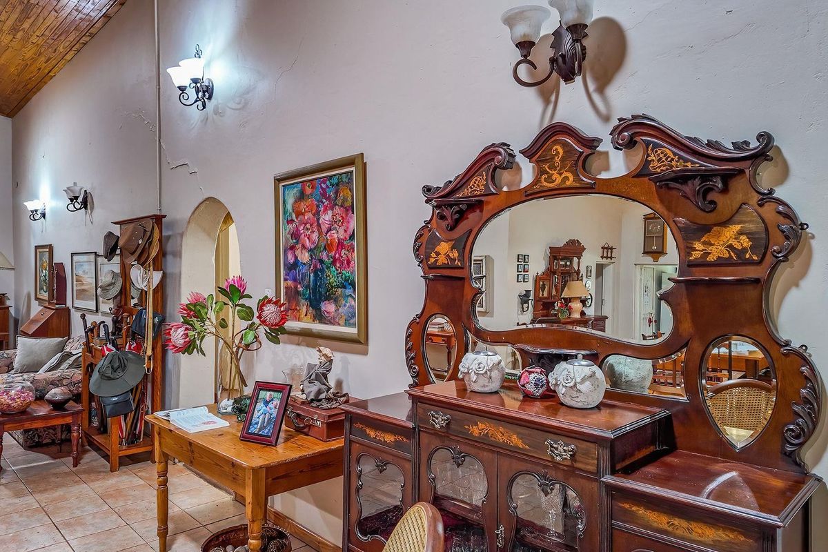 A spacious living area featuring high vaulted timber ceilings, tiled flooring, and arched doorways leading to adjacent rooms.