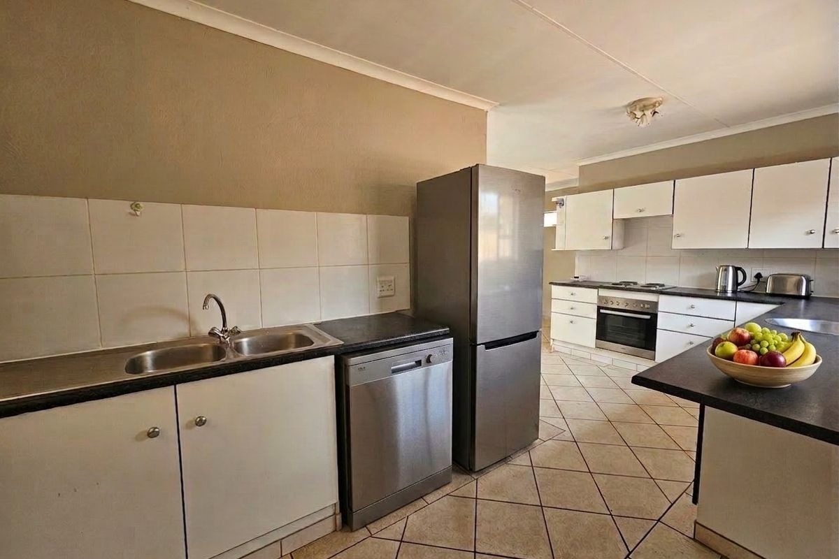 Functional kitchen featuring built-in cabinetry, a double basin sink, integrated oven and hob, and tiled flooring with a neutral backsplash.