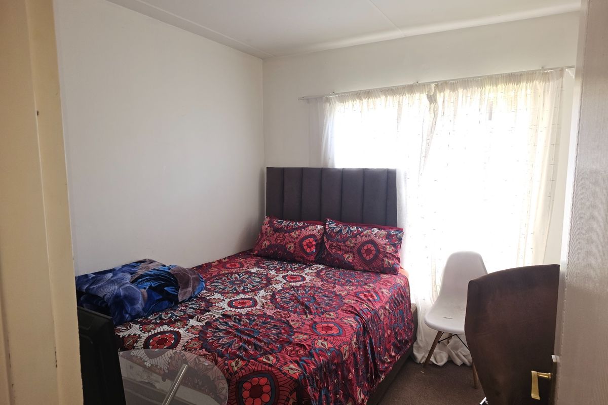 A standard bedroom featuring neutral walls and a window with a curtain rail, providing a functional space for rest.