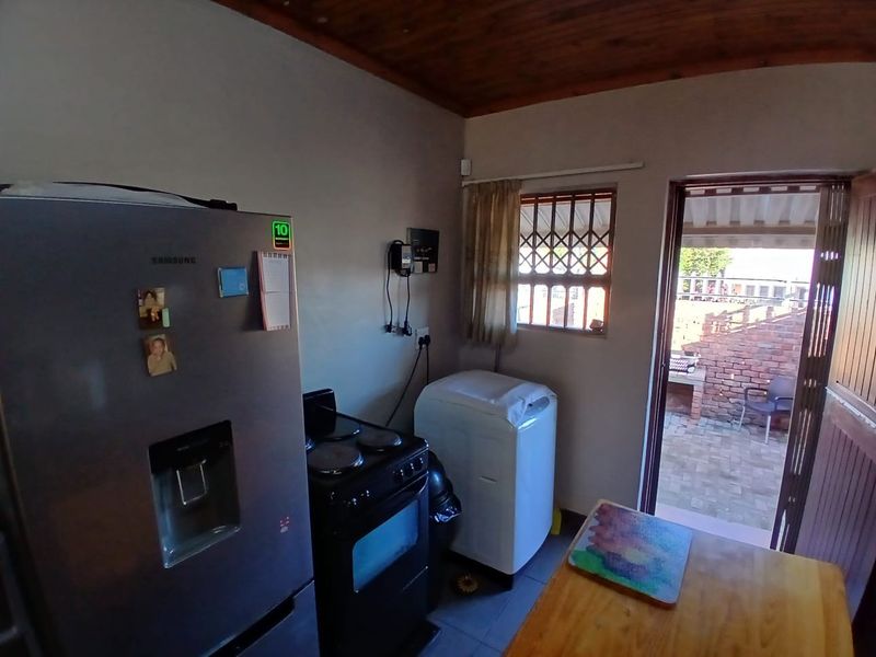A functional laundry area featuring tiled flooring, a timber ceiling, and direct access to an outdoor patio space.