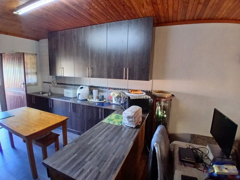 Kitchen featuring dark wood-look cabinetry, laminate countertops, and a timber-paneled ceiling, providing a functional workspace with integrated storage.
