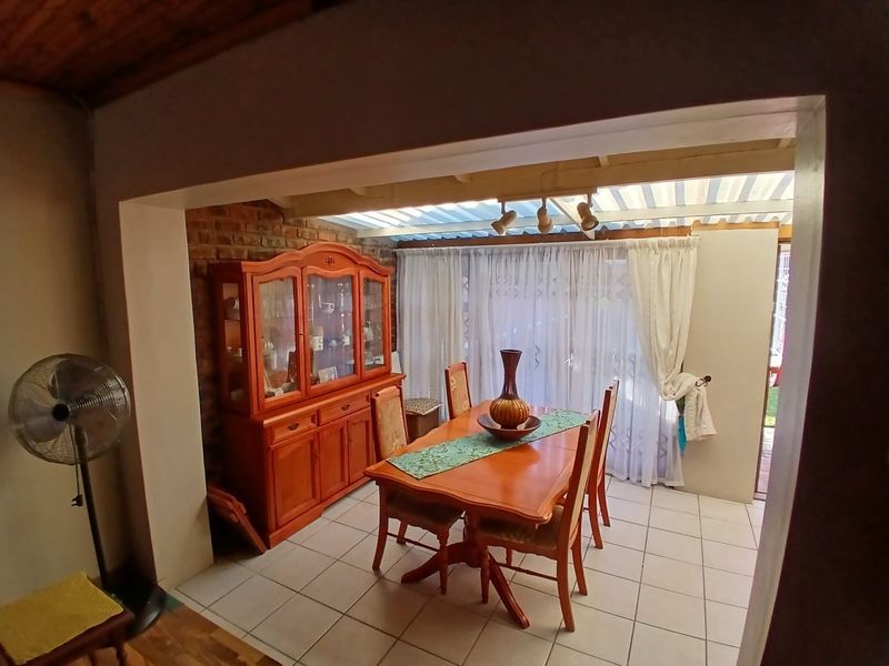 A dining area featuring tiled flooring, exposed brick wall accents, and a translucent roof structure providing natural light.