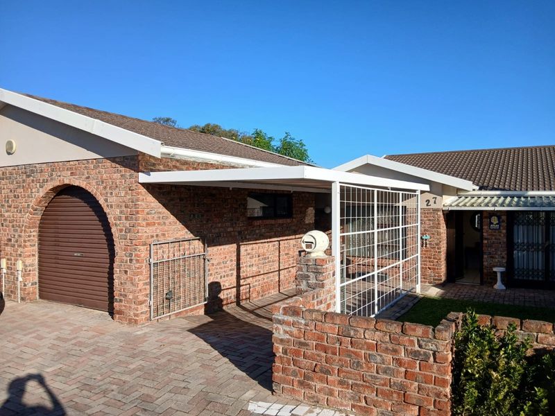 Front exterior view of a townhouse featuring a face-brick facade, a covered carport area, and a paved driveway entrance.
