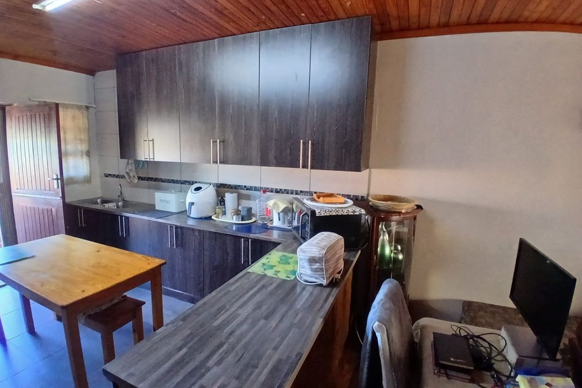 Kitchen featuring dark wood-look cabinetry, laminate countertops, and a timber-paneled ceiling, providing a functional workspace with integrated storage.