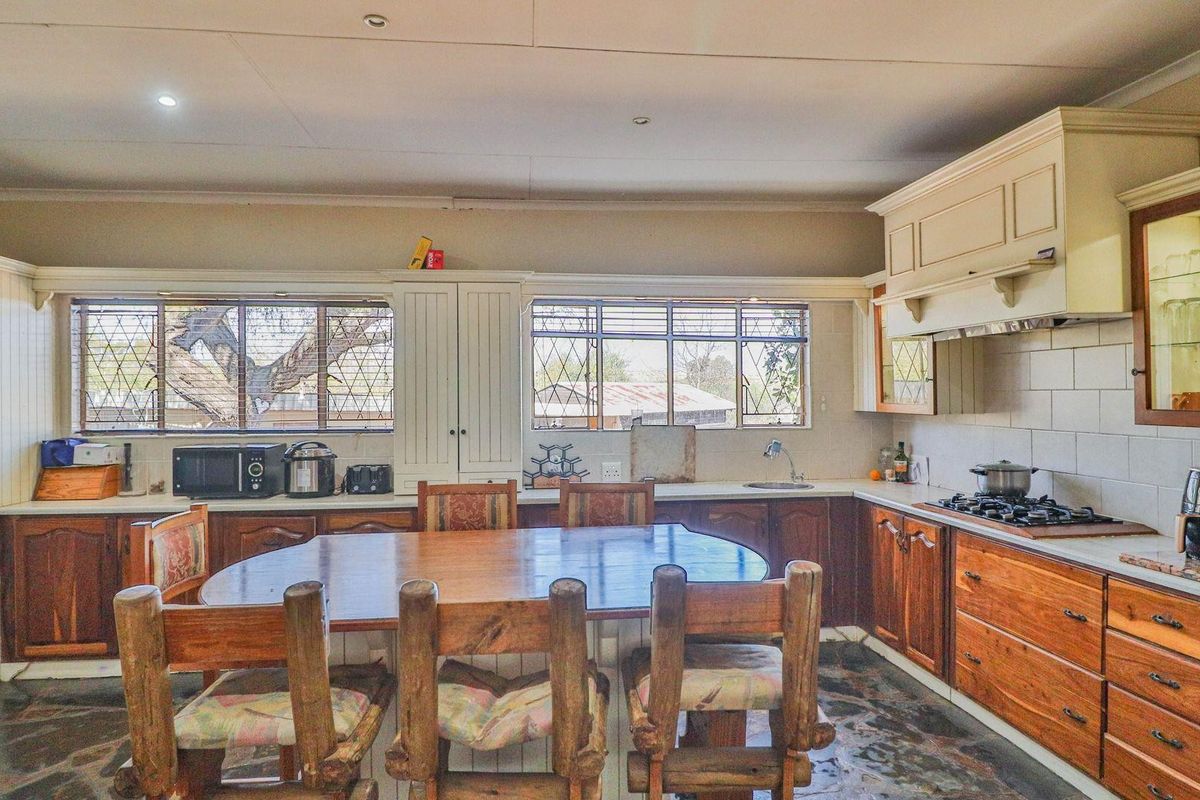 Spacious farmhouse kitchen featuring wooden cabinetry, integrated gas hob, built-in display shelving, and a large central dining area with natural light.