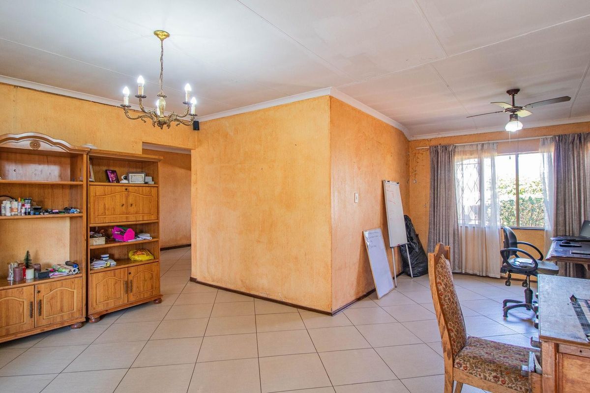 Spacious living area featuring tiled flooring, a ceiling fan, and a classic chandelier, offering a versatile layout for various living arrangements.