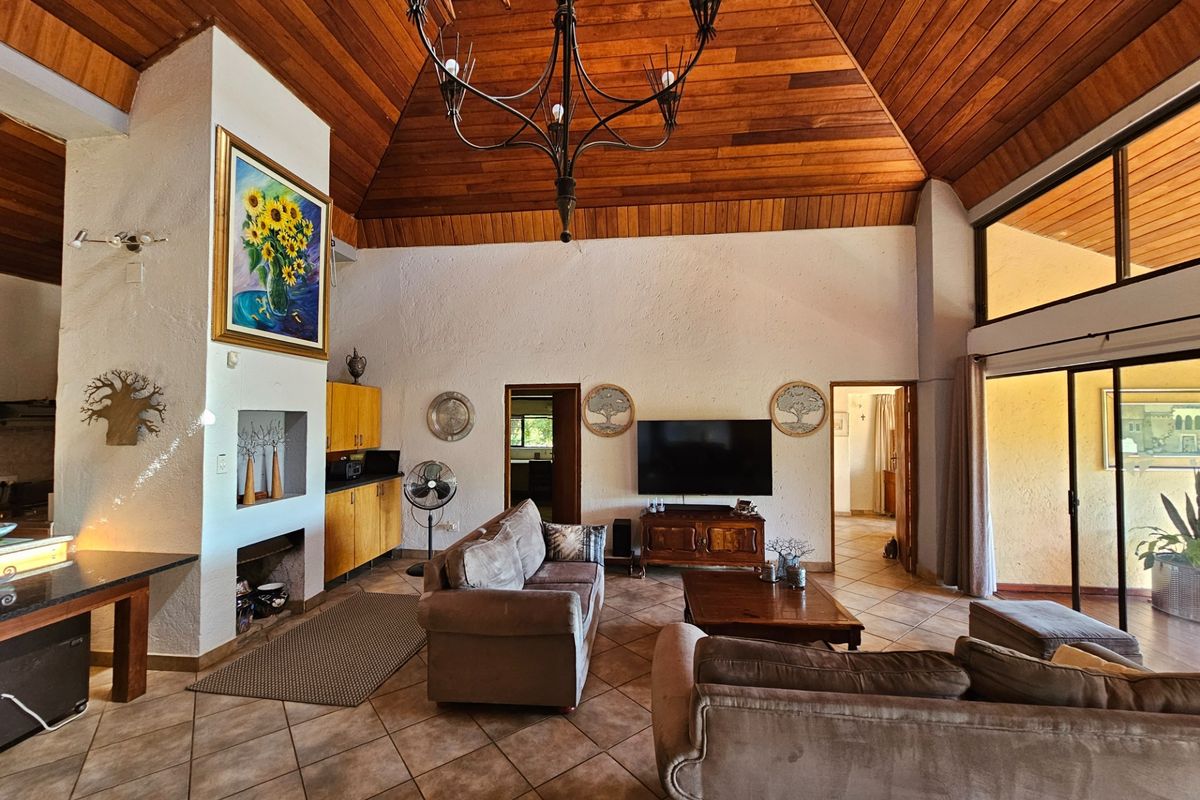 Spacious living area featuring a high vaulted timber ceiling, tiled flooring, a built-in fireplace, and large sliding doors leading to an outdoor space.