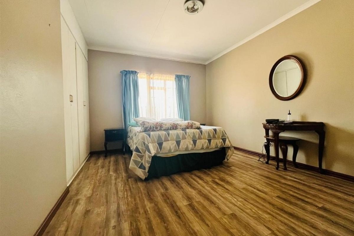 A bedroom featuring wood-look laminate flooring and built-in cupboards.