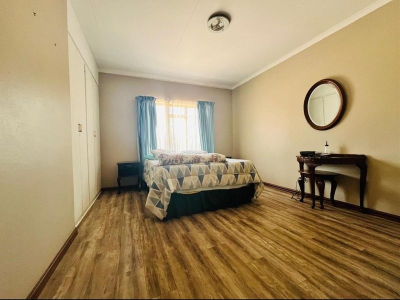 A bedroom featuring wood-look laminate flooring and built-in cupboards.