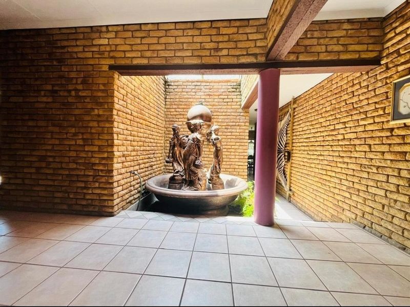 An internal courtyard area featuring exposed brick walls, tiled flooring, and a central decorative water fountain feature.